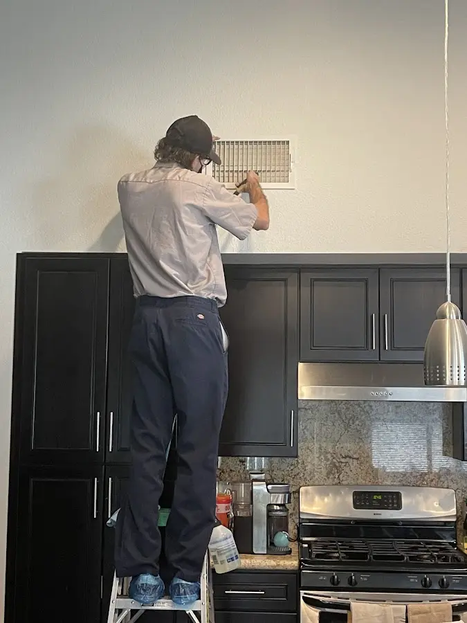Technician inspecting an air vent during HVAC service in Milan